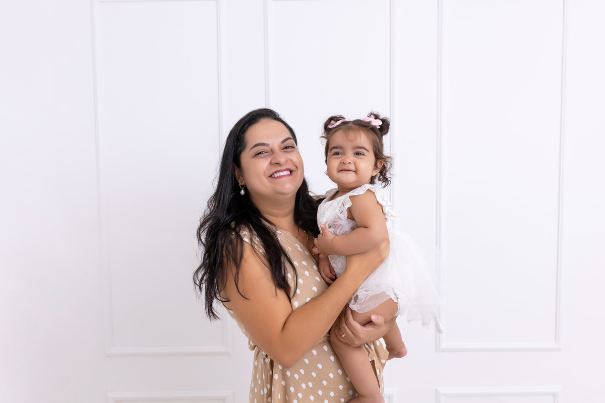 Bebê em ensaio Smash the Cake colorido com flores e raposinha em estúdio em Caraguatatuba, cenário personalizado em tons de rosa e laranja, criança sorrindo e brincando com o bolo de aniversário
