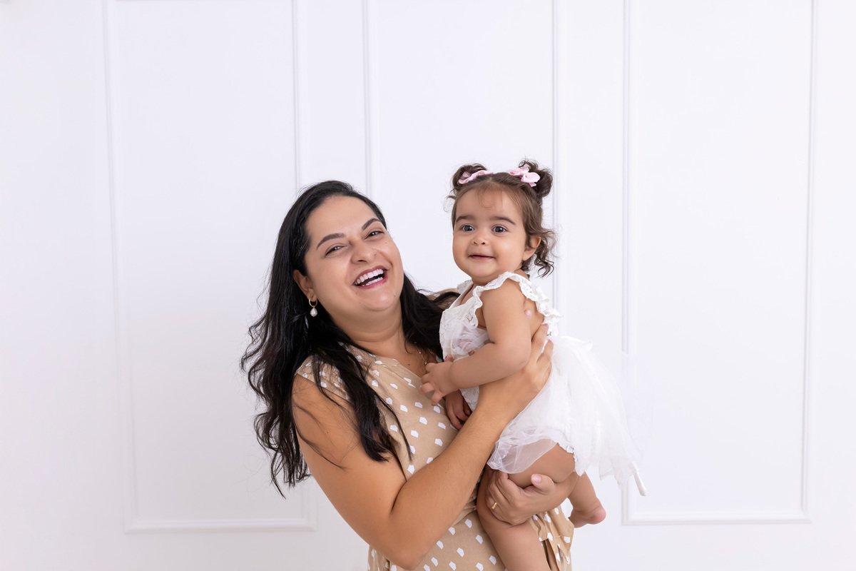 Bebê em ensaio Smash the Cake colorido com flores e raposinha em estúdio em Caraguatatuba, cenário personalizado em tons de rosa e laranja, criança sorrindo e brincando com o bolo de aniversário