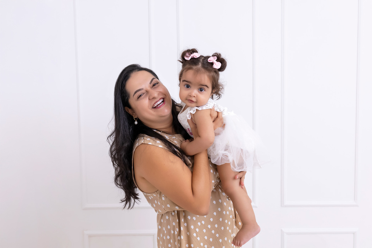 Bebê em ensaio Smash the Cake colorido com flores e raposinha em estúdio em Caraguatatuba, cenário personalizado em tons de rosa e laranja, criança sorrindo e brincando com o bolo de aniversário
