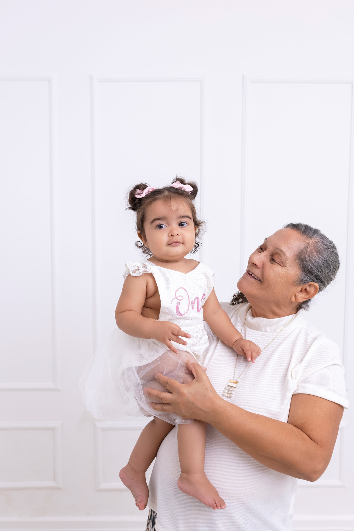 Bebê em ensaio Smash the Cake colorido com flores e raposinha em estúdio em Caraguatatuba, cenário personalizado em tons de rosa e laranja, criança sorrindo e brincando com o bolo de aniversário