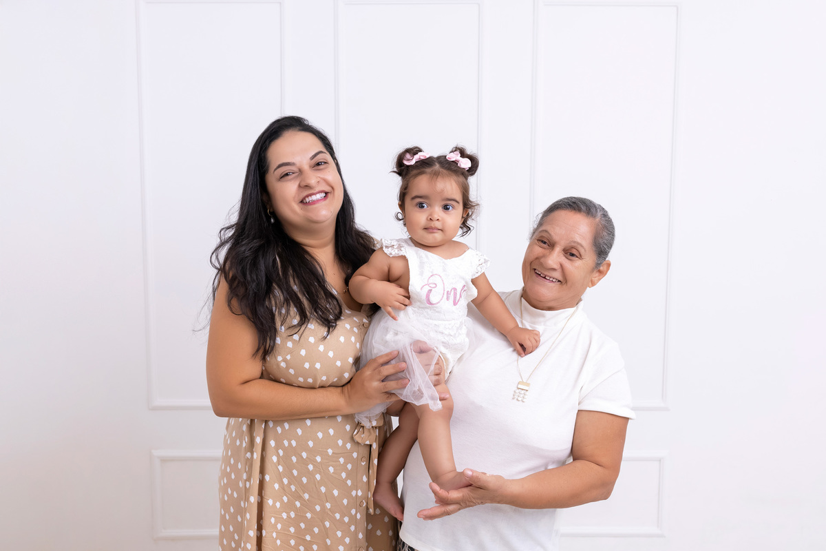 Bebê em ensaio Smash the Cake colorido com flores e raposinha em estúdio em Caraguatatuba, cenário personalizado em tons de rosa e laranja, criança sorrindo e brincando com o bolo de aniversário