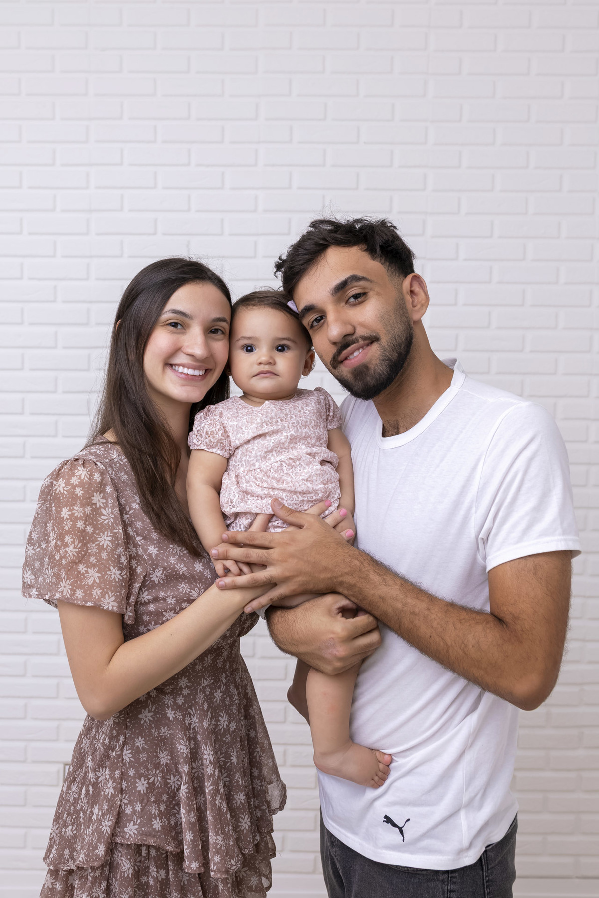 Bebê em ensaio Smash the Cake clean em estúdio branco com laços rosa, cenário minimalista e elegante, criança comendo e se lambuzando com bolo de aniversário em Caraguatatuba