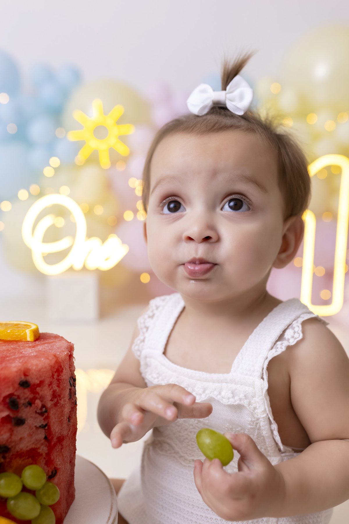 Bebê em ensaio Smash the Fruit tema sol com frutas frescas, cenário colorido e alegre, fotos de 1 ano em estúdio fotográfico em Caraguatatuba