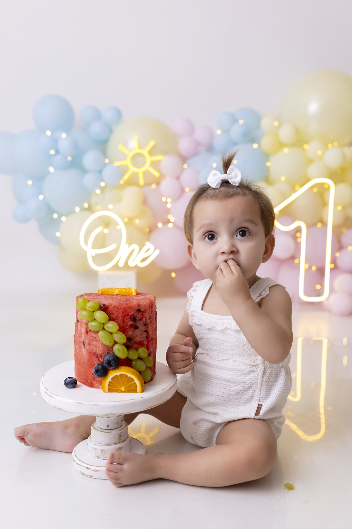 Bebê em ensaio Smash the Fruit tema sol com frutas frescas, cenário colorido e alegre, fotos de 1 ano em estúdio fotográfico em Caraguatatuba
