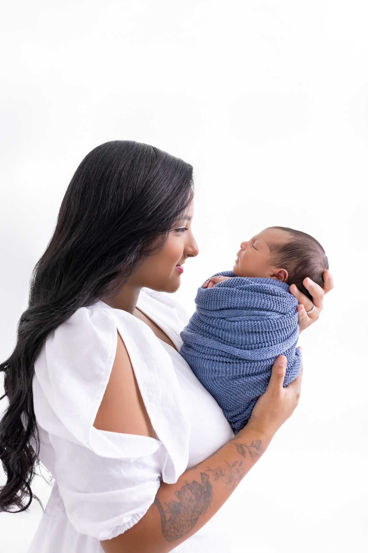 Pais segurando o bebê Bernardo recém-nascido durante ensaio newborn em estúdio em Caraguatatuba