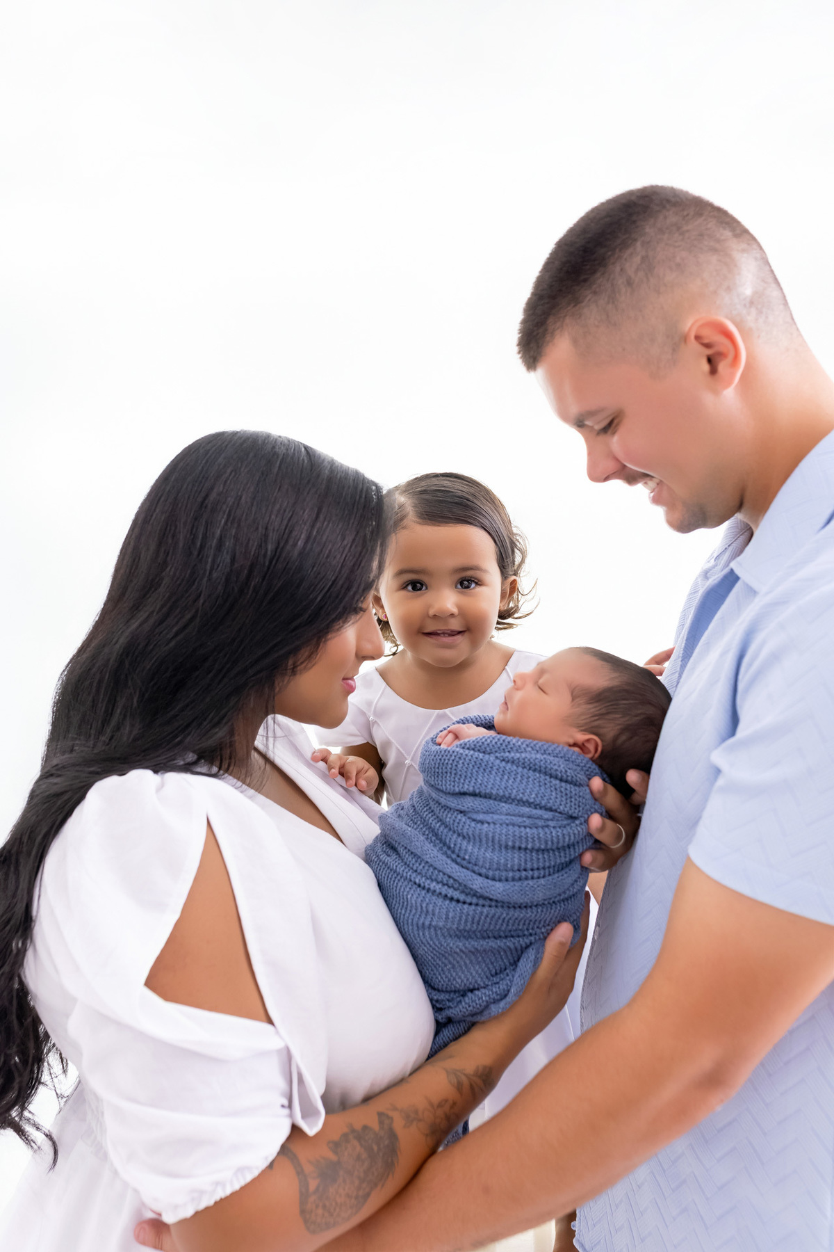 Pais segurando o bebê Bernardo recém-nascido durante ensaio newborn em estúdio em Caraguatatuba