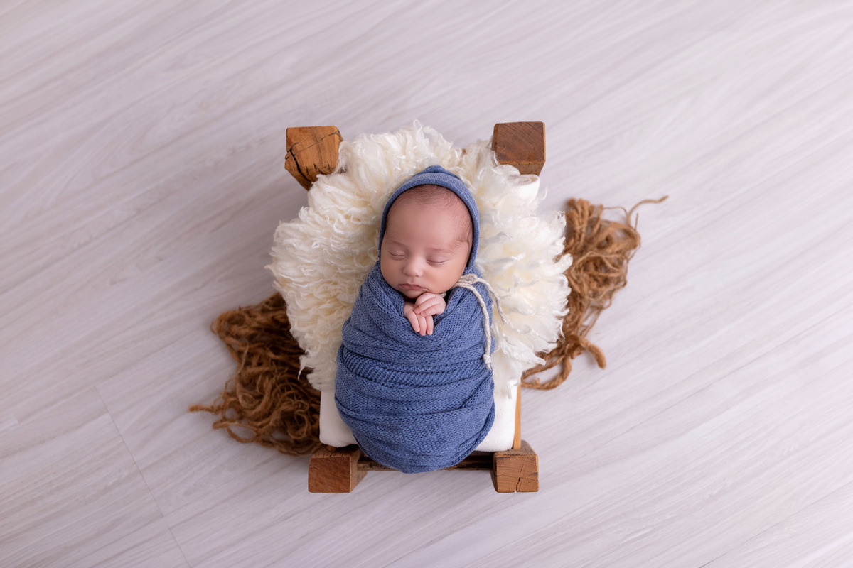 Bebê recém-nascido Levi enroladinho em tecido azul no baldinho durante ensaio newborn no estúdio On Click Fotografia em Caraguatatuba