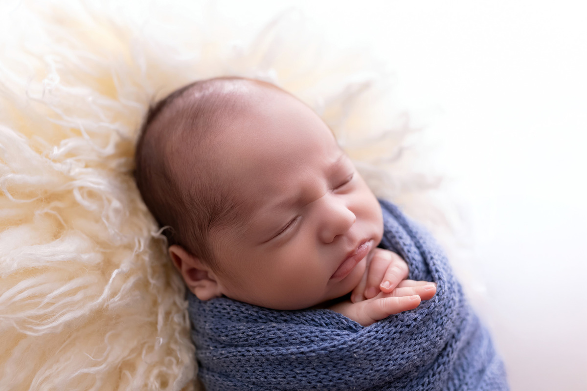 Bebê recém-nascido Levi enroladinho em tecido azul no baldinho durante ensaio newborn no estúdio On Click Fotografia em Caraguatatuba