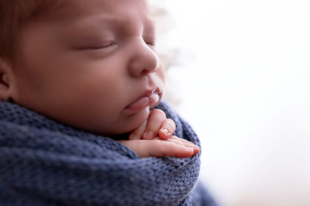 Bebê recém-nascido Levi enroladinho em tecido azul no baldinho durante ensaio newborn no estúdio On Click Fotografia em Caraguatatuba