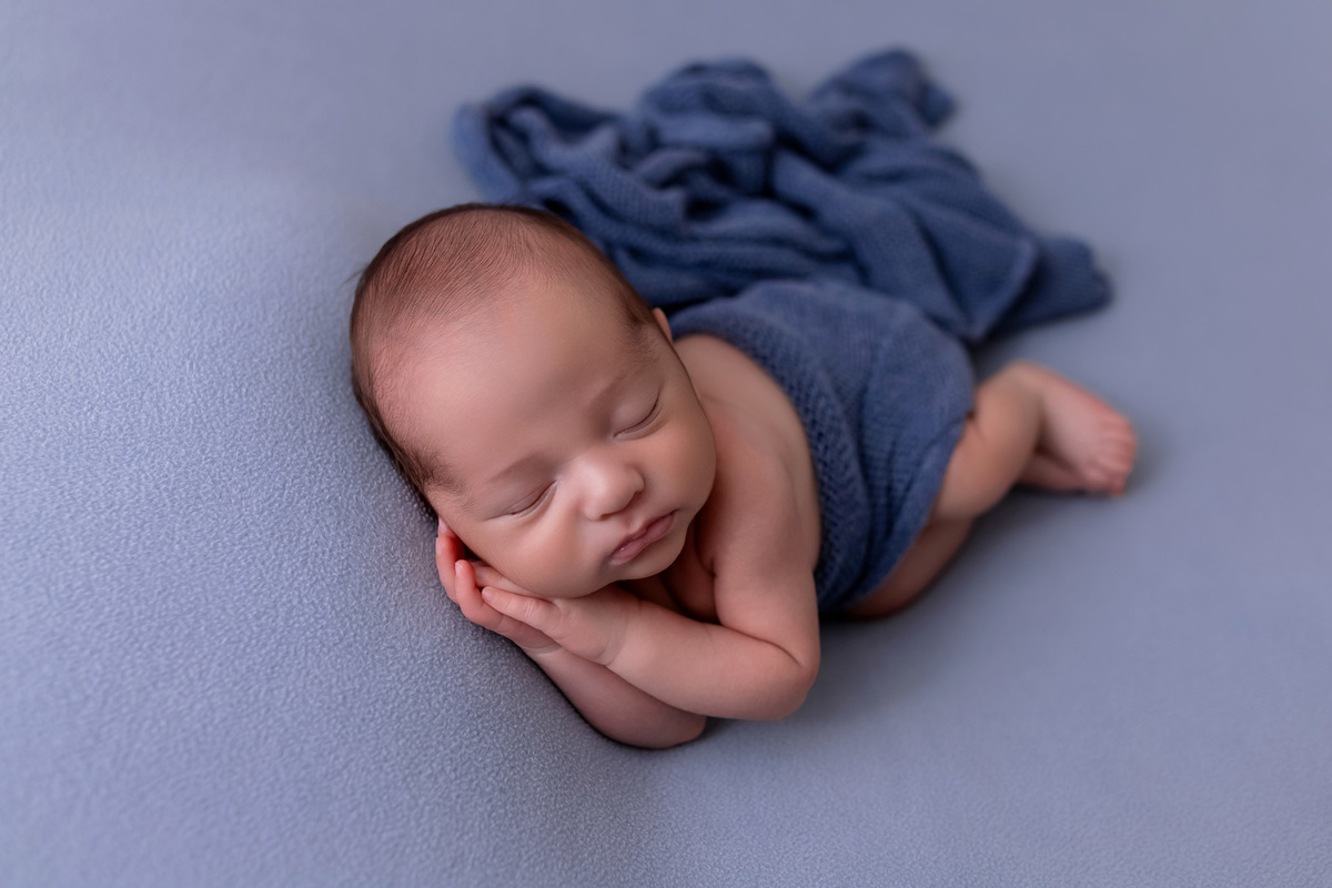 Bebê recém-nascido Levi enroladinho em tecido azul no baldinho durante ensaio newborn no estúdio On Click Fotografia em Caraguatatuba