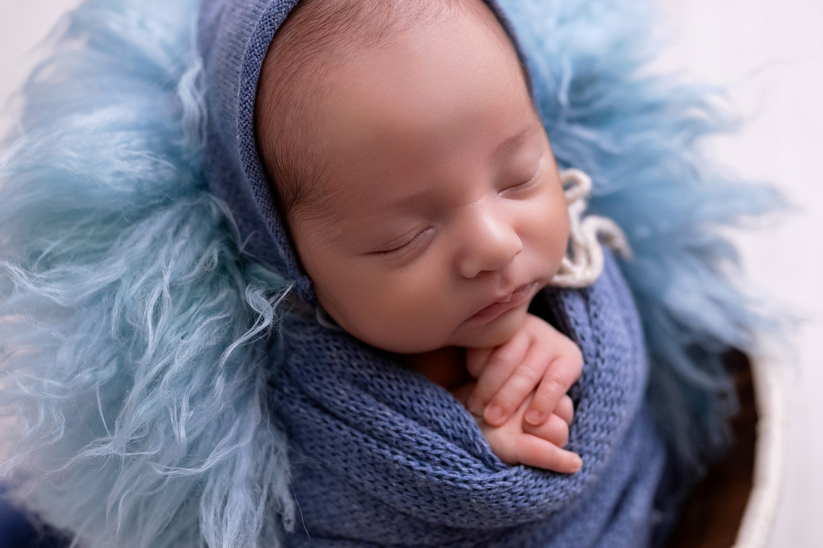 Bebê recém-nascido Levi enroladinho em tecido azul no baldinho durante ensaio newborn no estúdio On Click Fotografia em Caraguatatuba