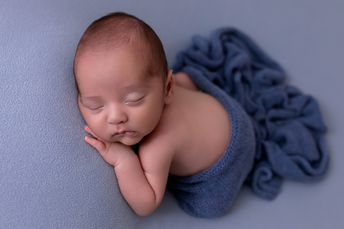 Bebê recém-nascido Levi enroladinho em tecido azul no baldinho durante ensaio newborn no estúdio On Click Fotografia em Caraguatatuba