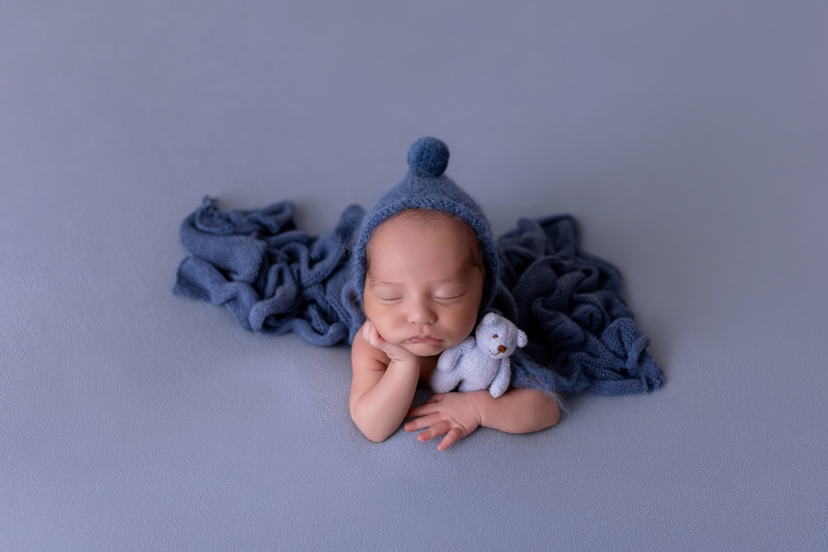 Bebê recém-nascido Levi enroladinho em tecido azul no baldinho durante ensaio newborn no estúdio On Click Fotografia em Caraguatatuba