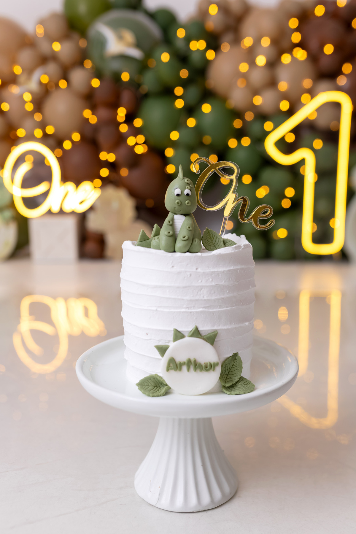 Bebê Arthur sorrindo no ensaio smash the cake tema baby dinossauro no estúdio On Click Fotografia em Caraguatatuba