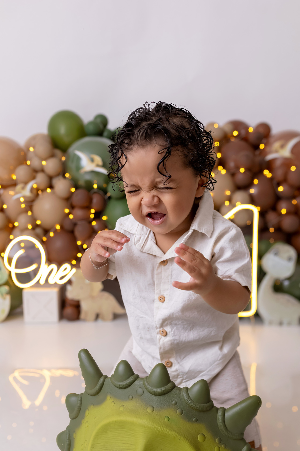 Bebê Arthur sorrindo no ensaio smash the cake tema baby dinossauro no estúdio On Click Fotografia em Caraguatatuba