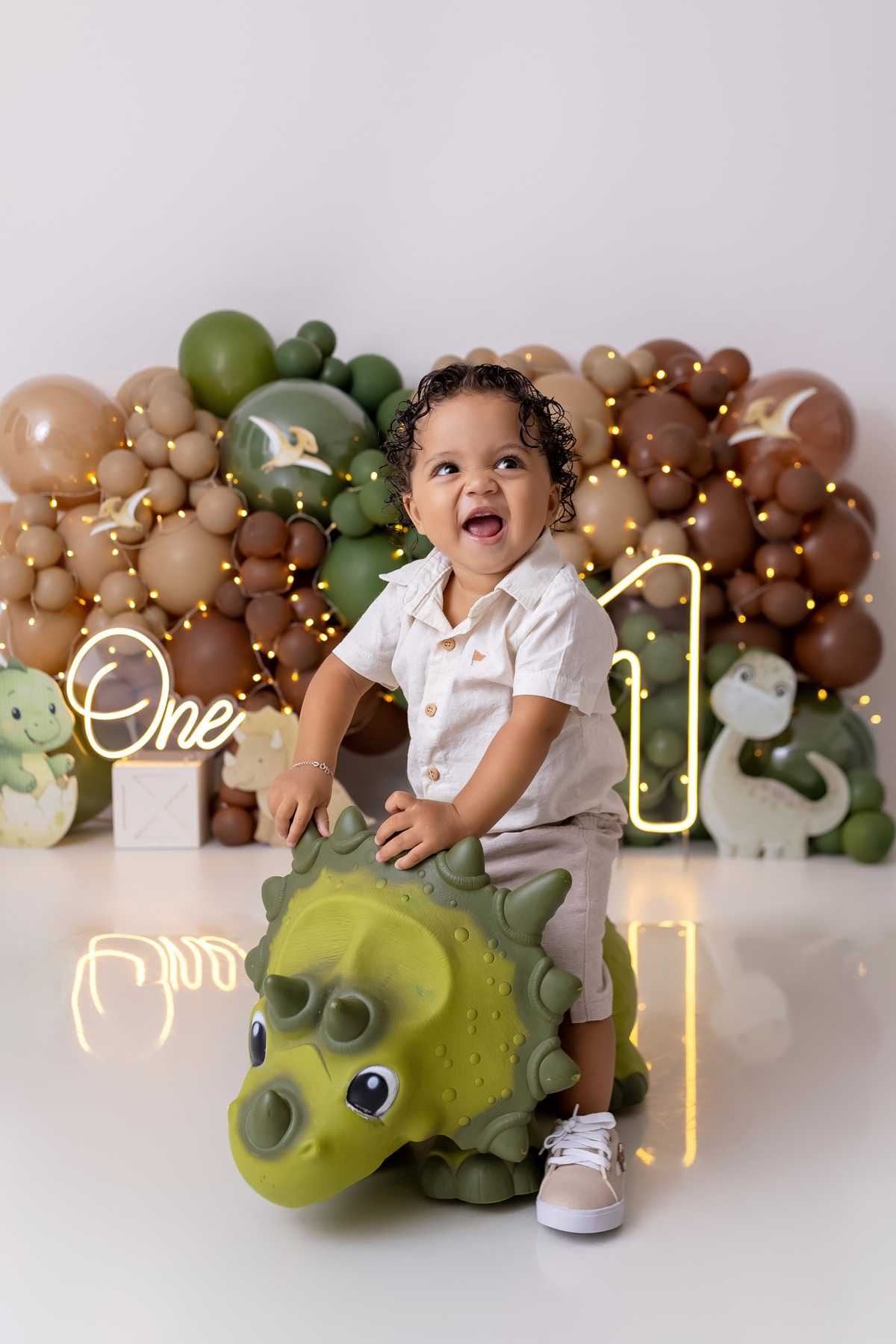 Bebê Arthur sorrindo no ensaio smash the cake tema baby dinossauro no estúdio On Click Fotografia em Caraguatatuba