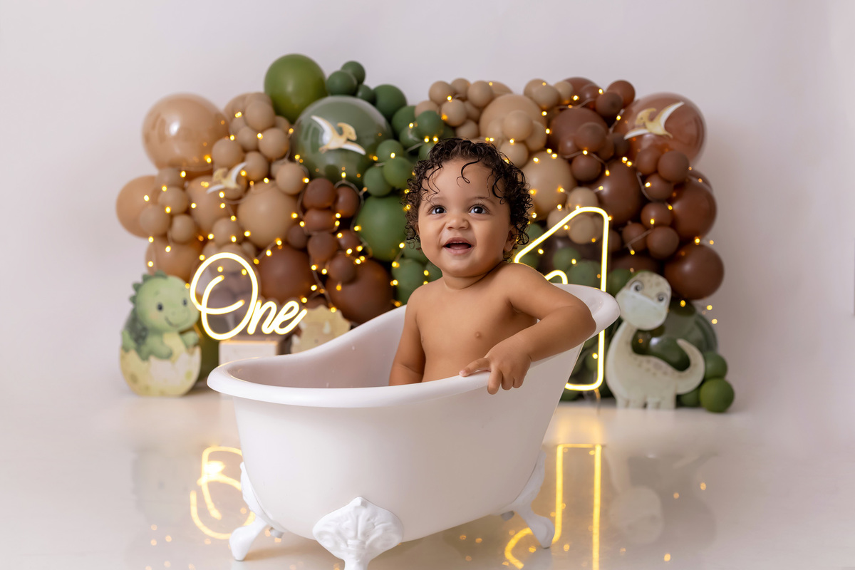 Bebê Arthur sorrindo no ensaio smash the cake tema baby dinossauro no estúdio On Click Fotografia em Caraguatatuba