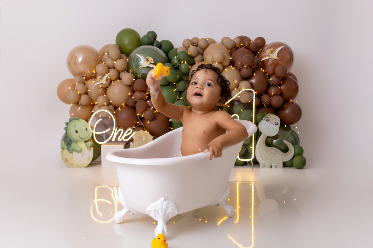 Bebê Arthur sorrindo no ensaio smash the cake tema baby dinossauro no estúdio On Click Fotografia em Caraguatatuba