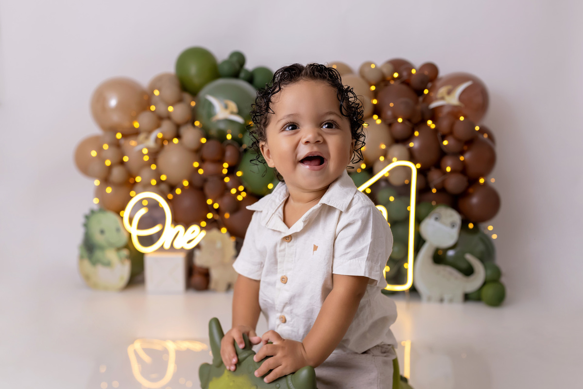 Bebê Arthur sorrindo no ensaio smash the cake tema baby dinossauro no estúdio On Click Fotografia em Caraguatatuba