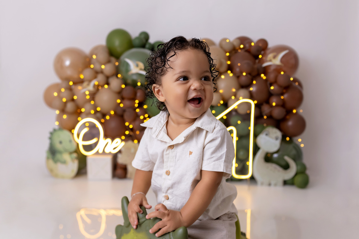Bebê Arthur sorrindo no ensaio smash the cake tema baby dinossauro no estúdio On Click Fotografia em Caraguatatuba