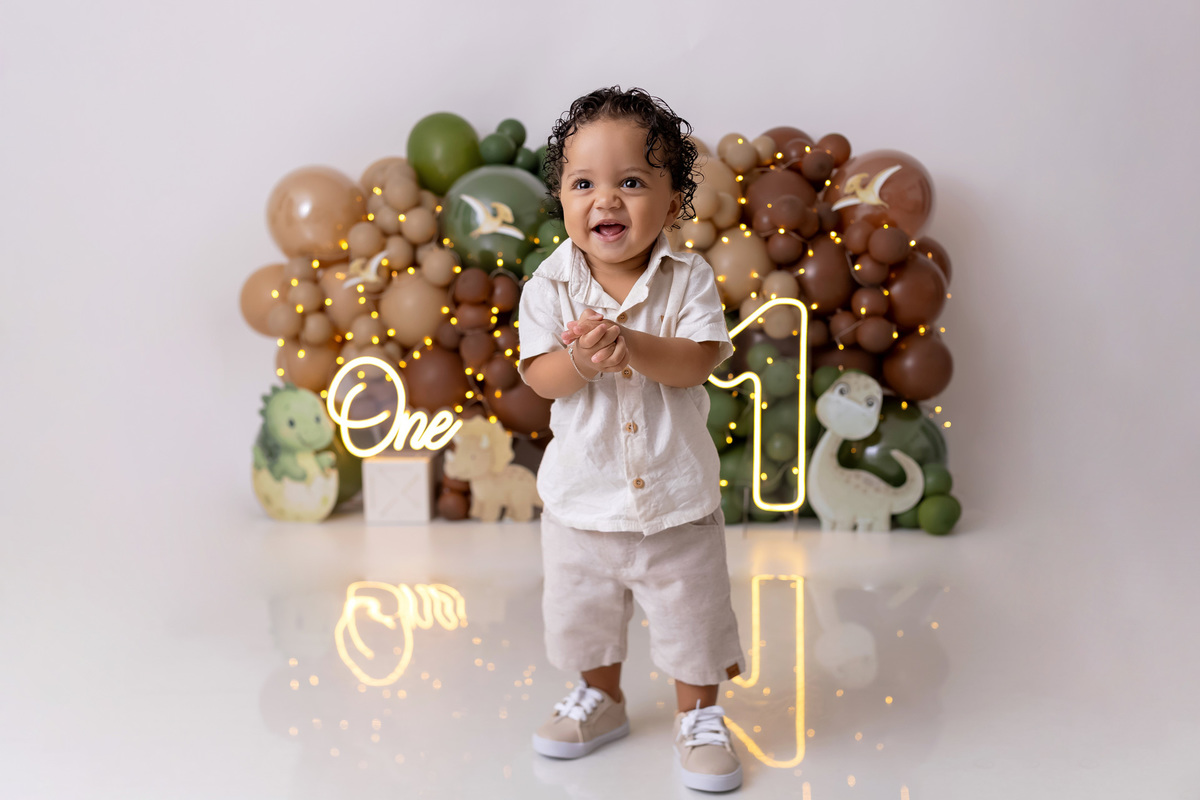 Bebê Arthur sorrindo no ensaio smash the cake tema baby dinossauro no estúdio On Click Fotografia em Caraguatatuba