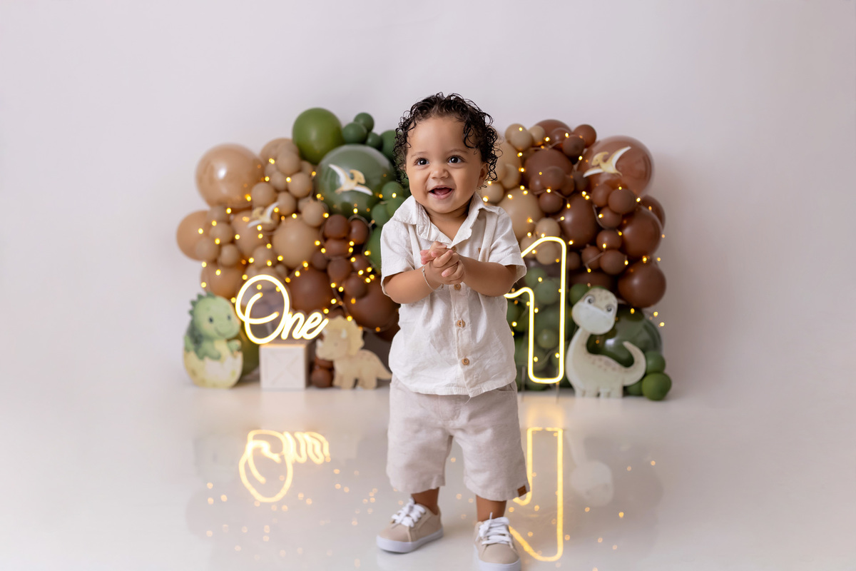 Bebê Arthur sorrindo no ensaio smash the cake tema baby dinossauro no estúdio On Click Fotografia em Caraguatatuba