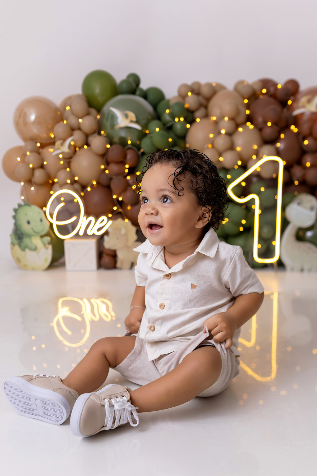 Bebê Arthur sorrindo no ensaio smash the cake tema baby dinossauro no estúdio On Click Fotografia em Caraguatatuba
