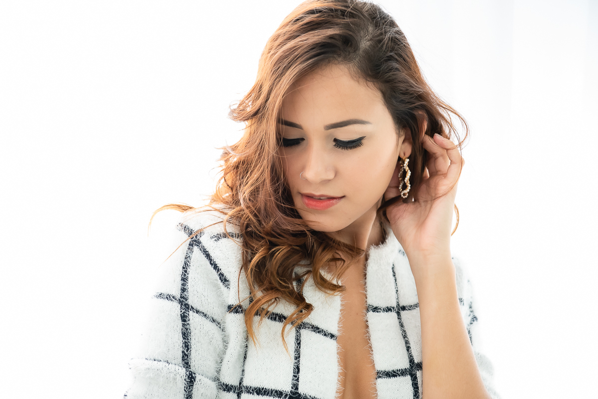 modelo com blusa xadrez branca e preto fazendo pose para ensaio sensual boudoir feminino no estudio 