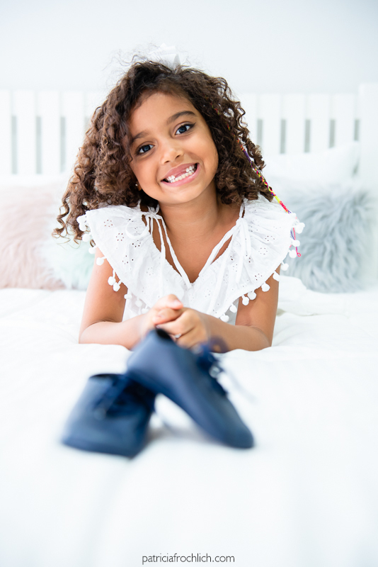 Ensaio fotografico familia e gestante. Menina faz pose com sapatinho azul de bebê, esperando a chegada do irmãozinho. Ensaio em estudio na Gloria Zona Sul do Rio de Janeiro com luz natural 
