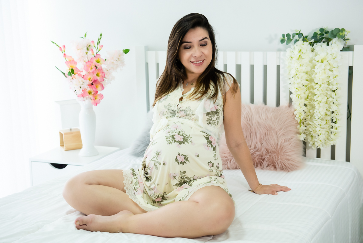 gestante sentada na cama branca em ensaio gestante gravida em estúdio com luz natural
