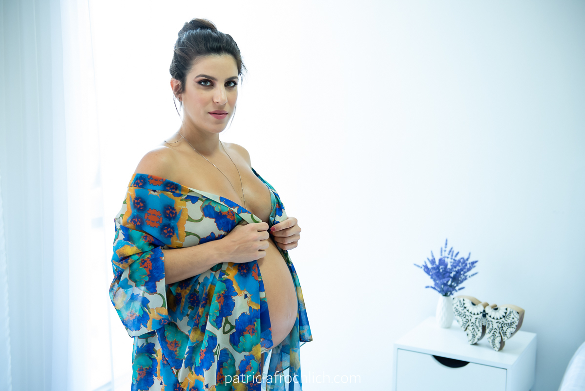 mulher gravida em pe com roupa azul. parede branca. ensaio gestante estúdio rio de janeiro. ensaio com luz natural. ensaio feminino.