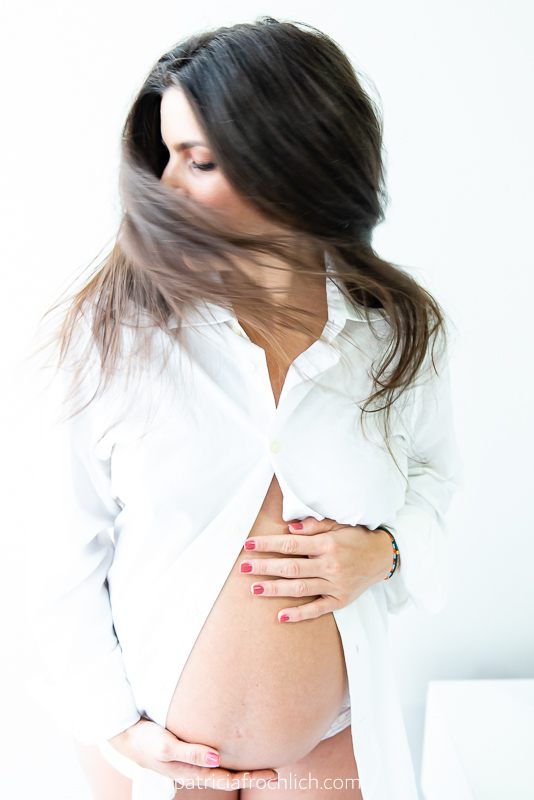 mulher gravida com blusa branca brinca com o cabelo. ensaio gestante estúdio rio de janeiro. ensaio com luz natural. ensaio feminino.