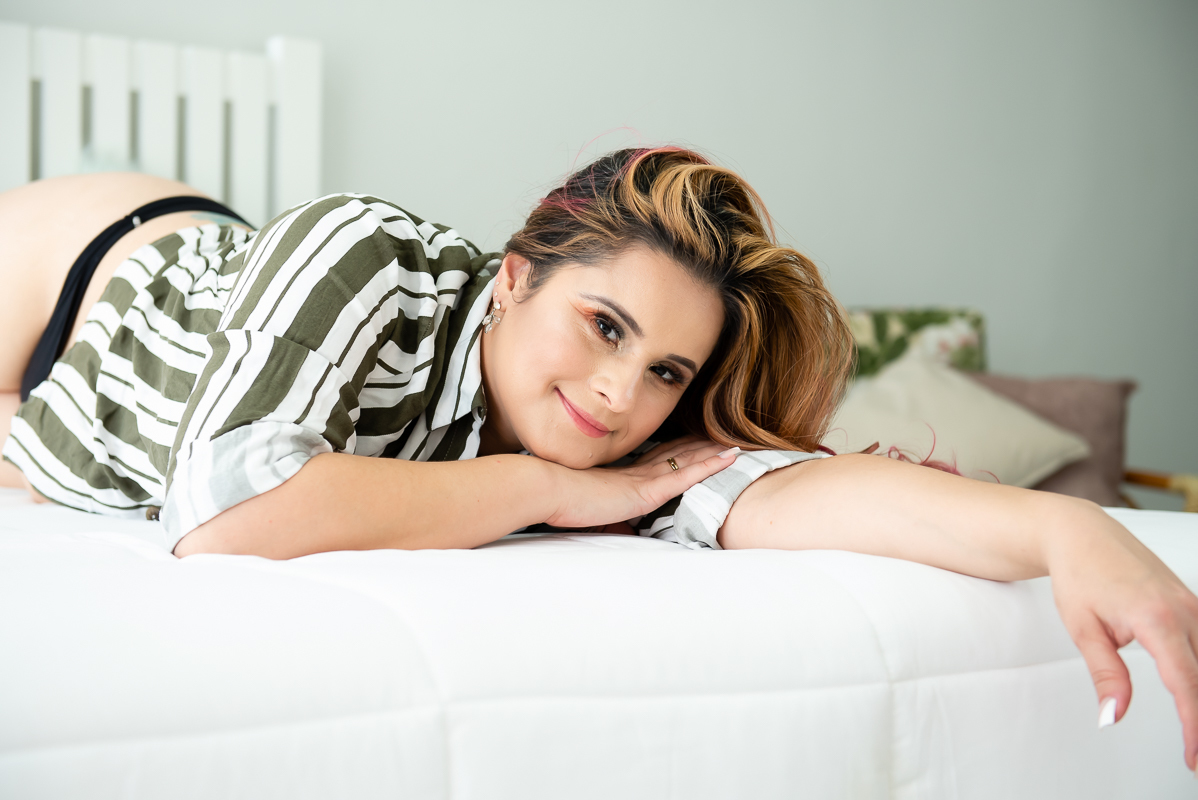 mulher sorrindo deitada na cama posando para ensaio sensual no rio de janeiro
