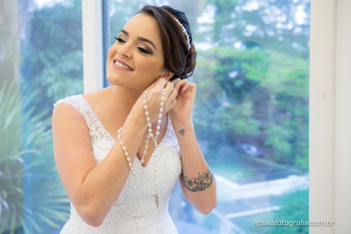 noiva colocando o brinco no salão de beleza Maison Payout na Granja Julieta