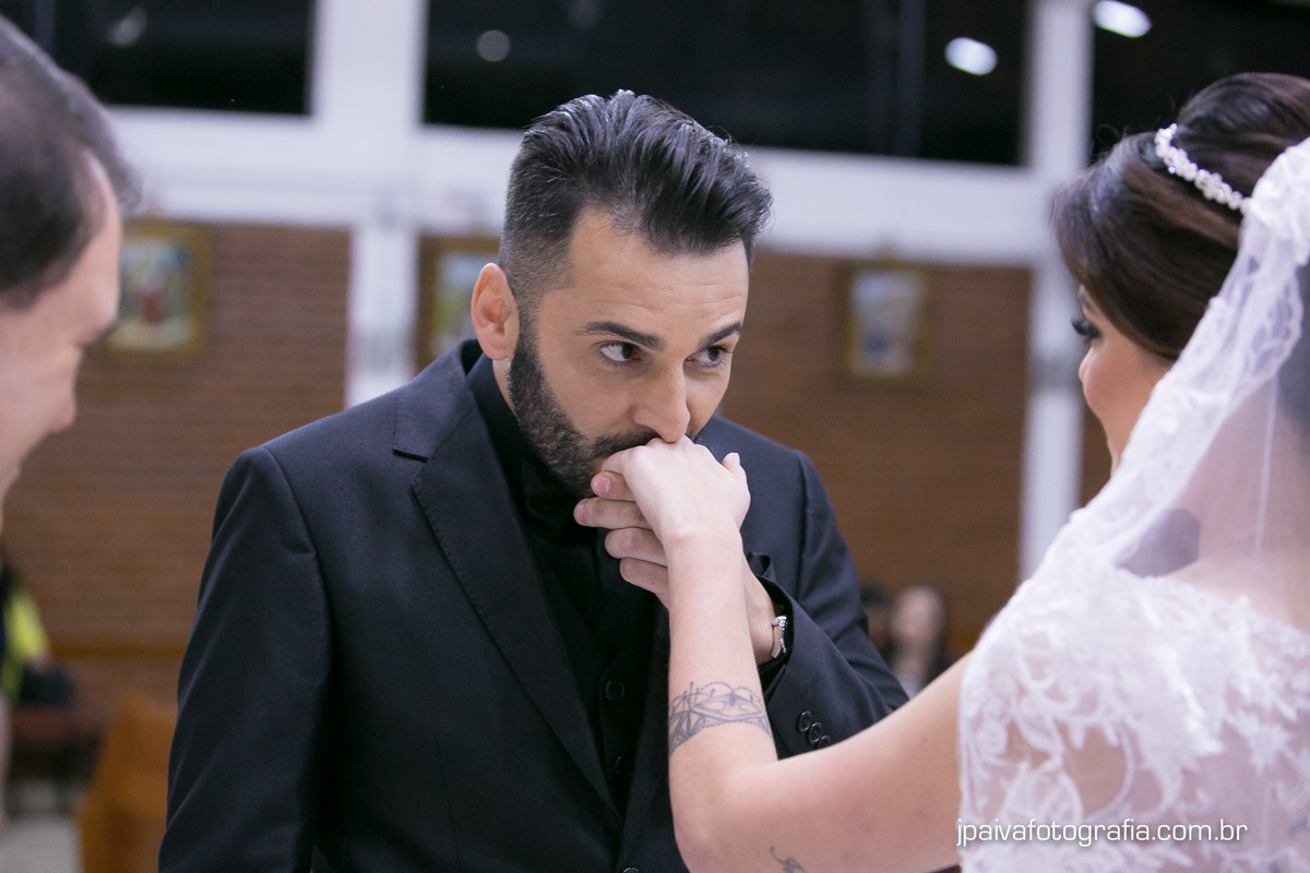 Noivo beijando mão da noiva após a troca de alianças no altar durante o casamento Mariana e Rogerio na  igreja Paróquia Sagrada Família Diocese de Santo Amaro