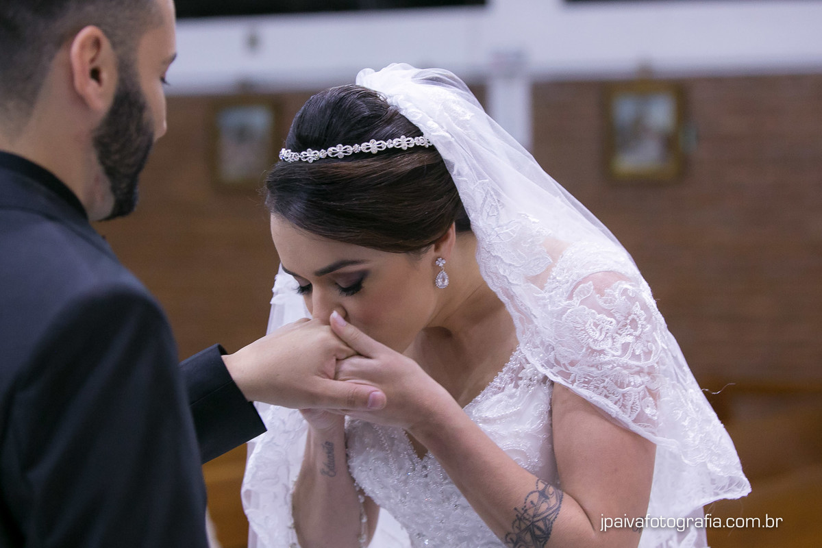 Noivo beijando mão da noiva após a troca de alianças no altar durante o casamento Mariana e Rogerio na  igreja Paróquia Sagrada Família Diocese de Santo Amaro