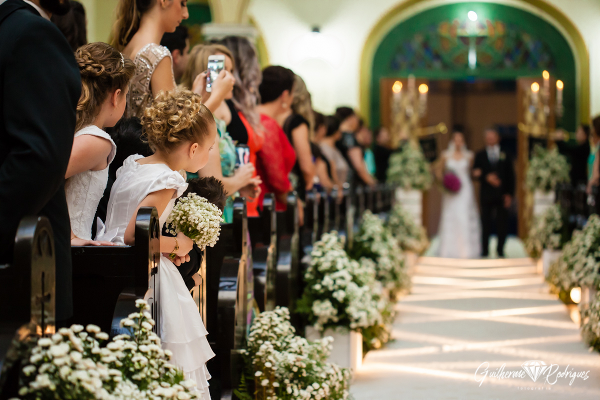 Criança espiando a noiva entrar na igreja. Fotógrafo de casamentos Guilherme Rodrigues.