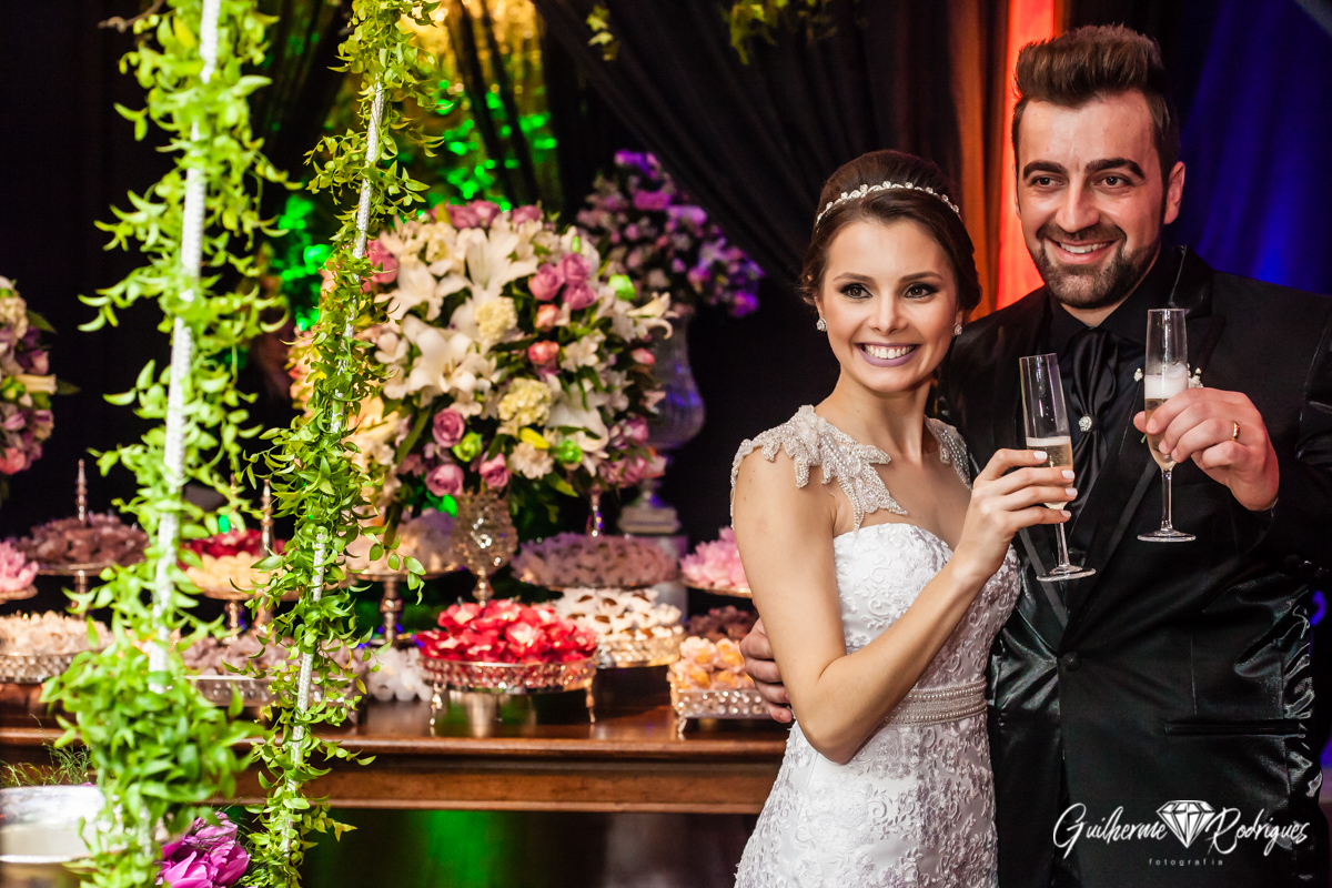 Noivos na frente da mesa de doces brindando