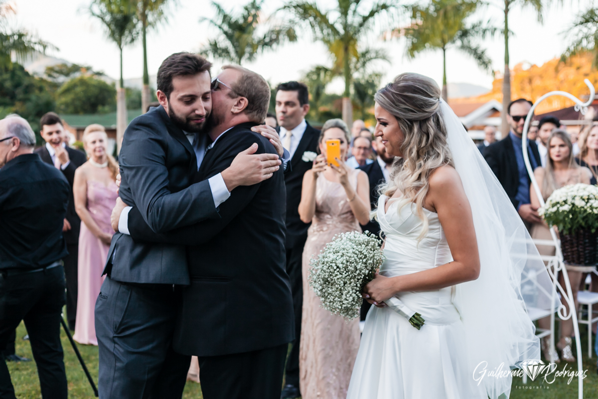 A chegada da noiva ao altar. Noivo abraçando o sogro. Fotos Guilherme Rodrigues.