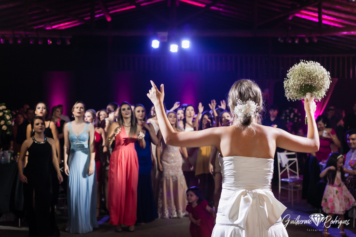 Noiva jogando o buque para as solteiras na festa do seu casamento. Fotos do melhor fotógrafo.
