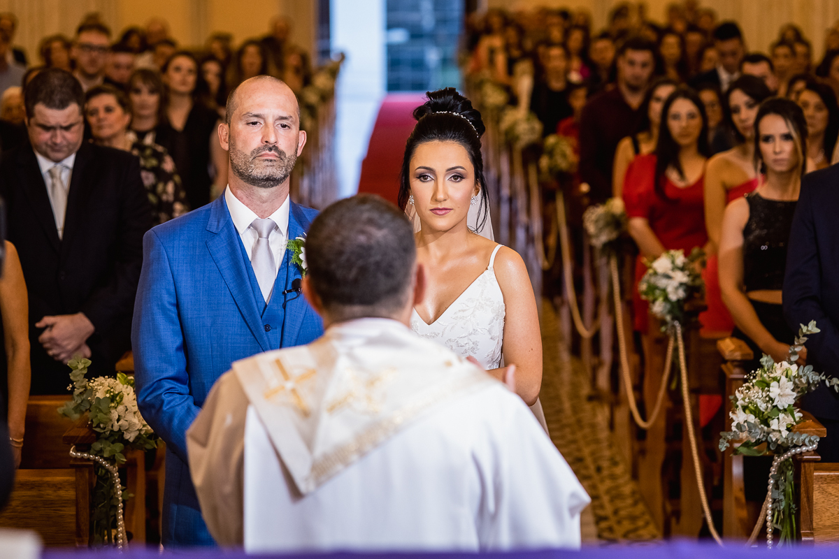 O vestido de noiva, muitas vezes o centro das atenções, brilha com elegância enquanto ela caminha em direção ao altar. 