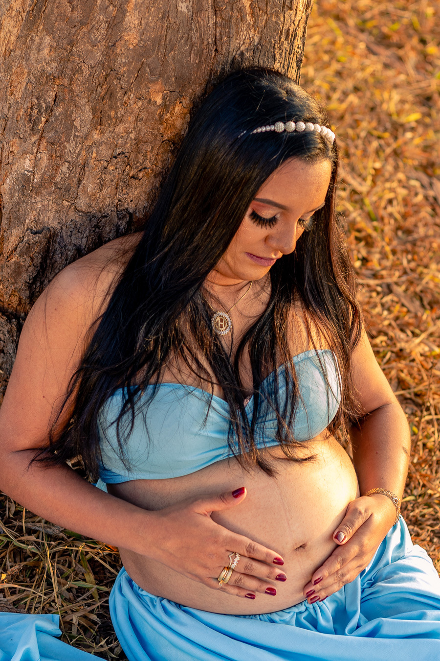 Heloisa sentada debaixo da arvore olhando a barriga, foto realizada pelo fotografo Anderson Rezende