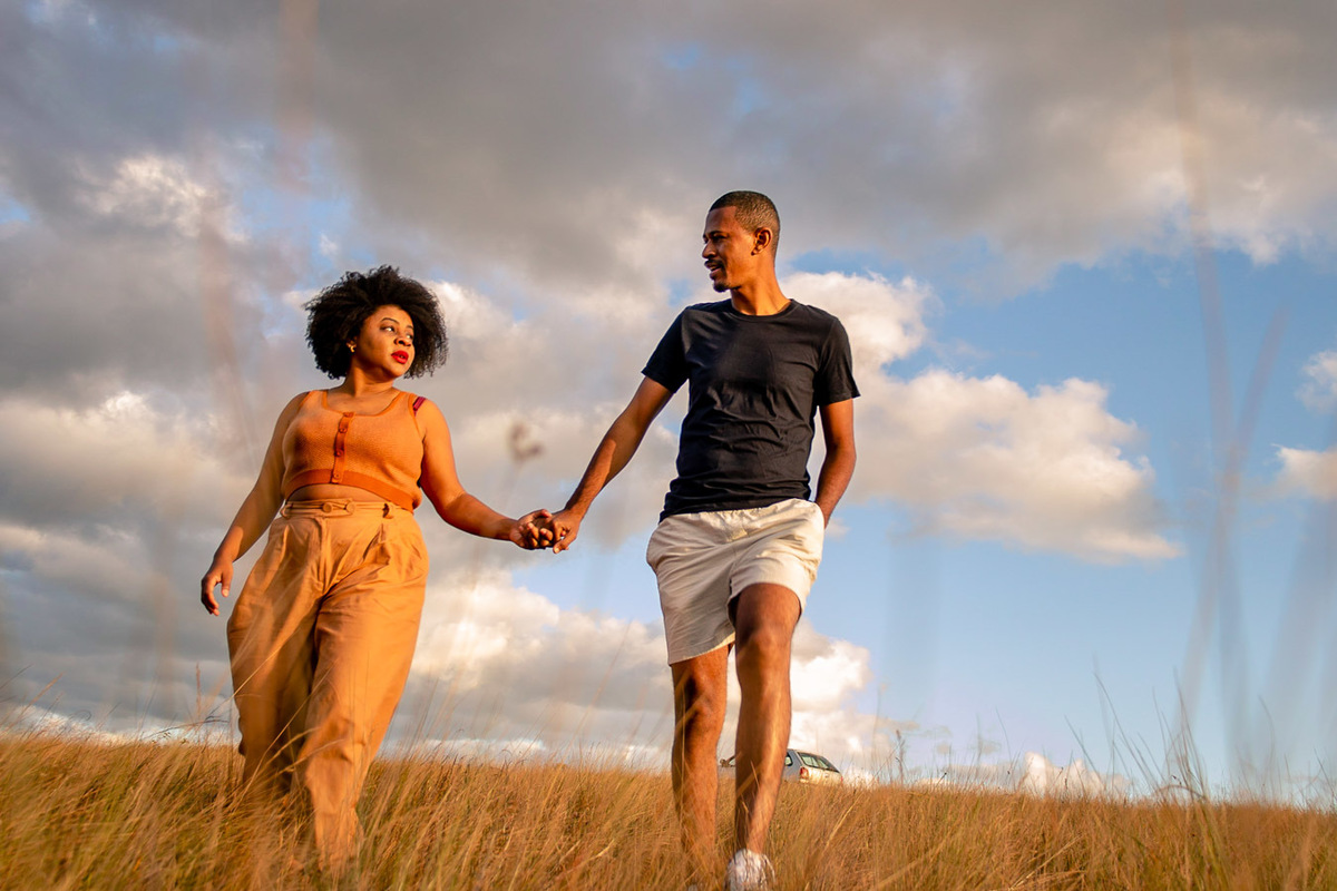 Fran e Tiago andando na mata com o céu com nuvens no fundo