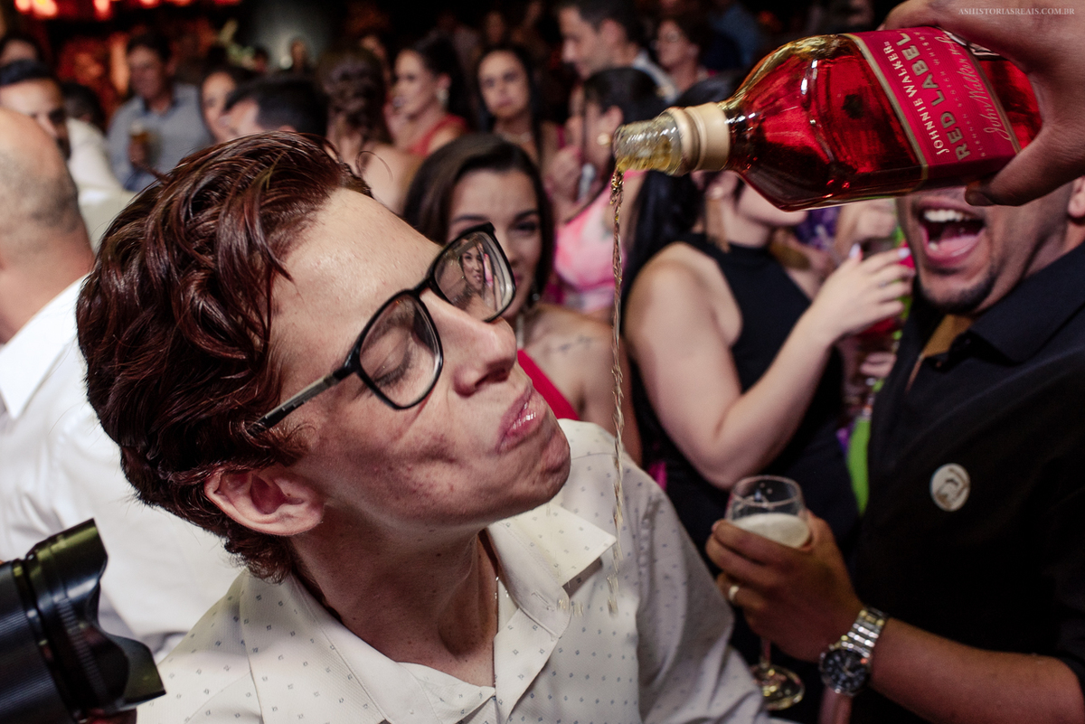 Convidados virando garrafa de whisky na boca na festa de casamento em Tiradentes.