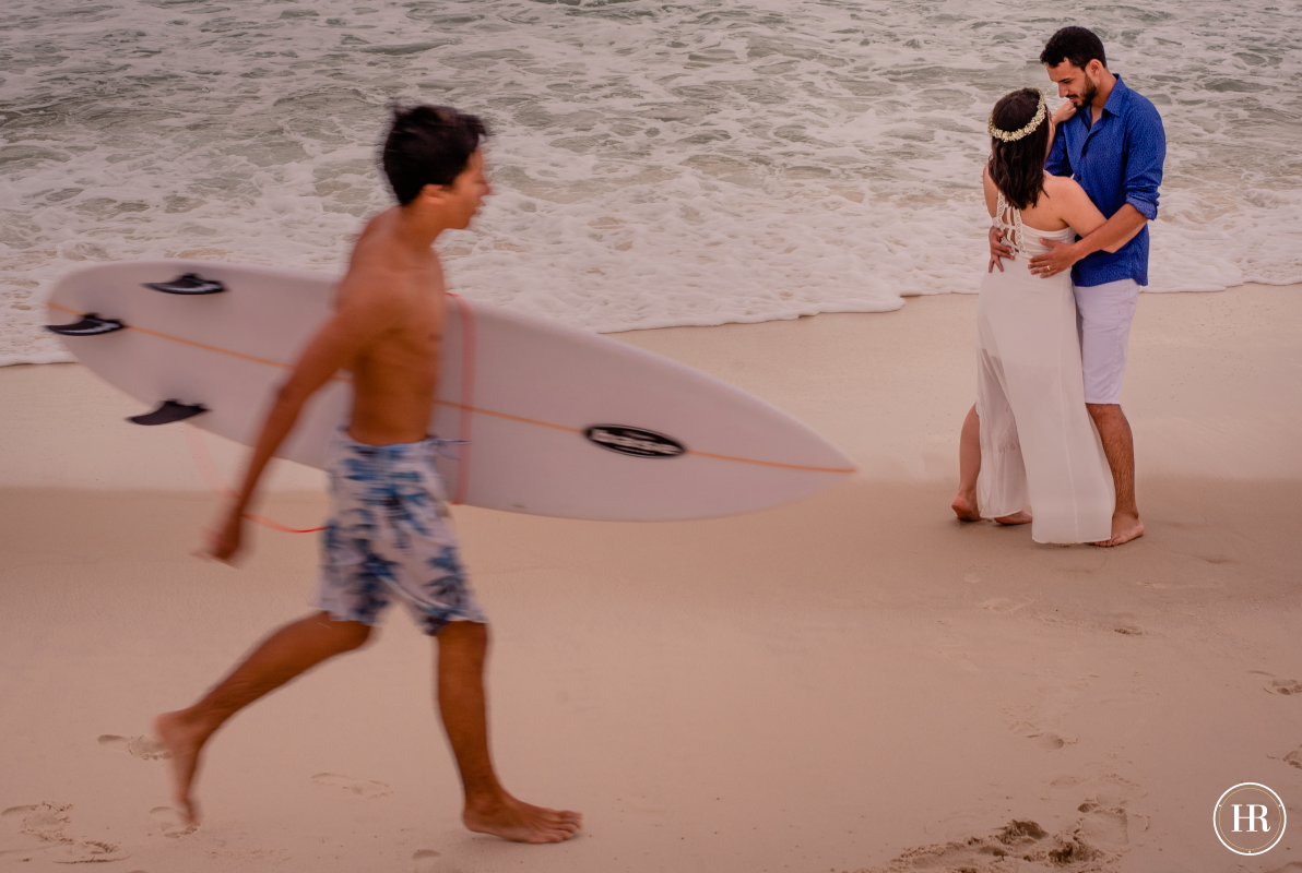 Ensaio com surfista na praia com os noivos na areia.