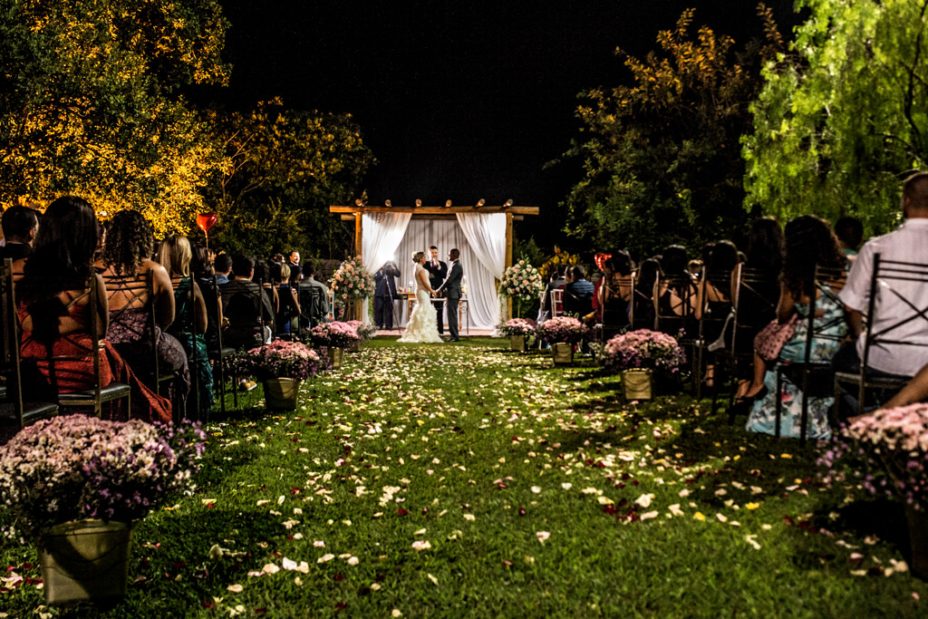 Uma vista aberta da cerimônia com os noivos ao fundo recebendo a benção