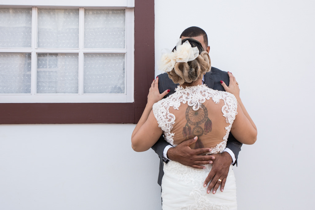 aquele abraço, onde mostra os detalhes lindos do vestido da noiva e suas tatuagens