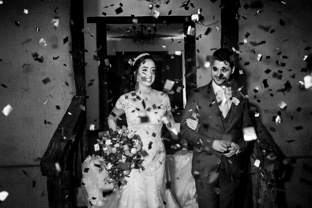 A entrada triunfal dos noivos na recepção com chuva de papeis