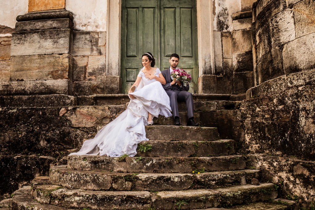 sentado na escadaria da igreja nossa senhora do rosário de ouro preto rochele vestindo seu sapato e euler segurando o buque