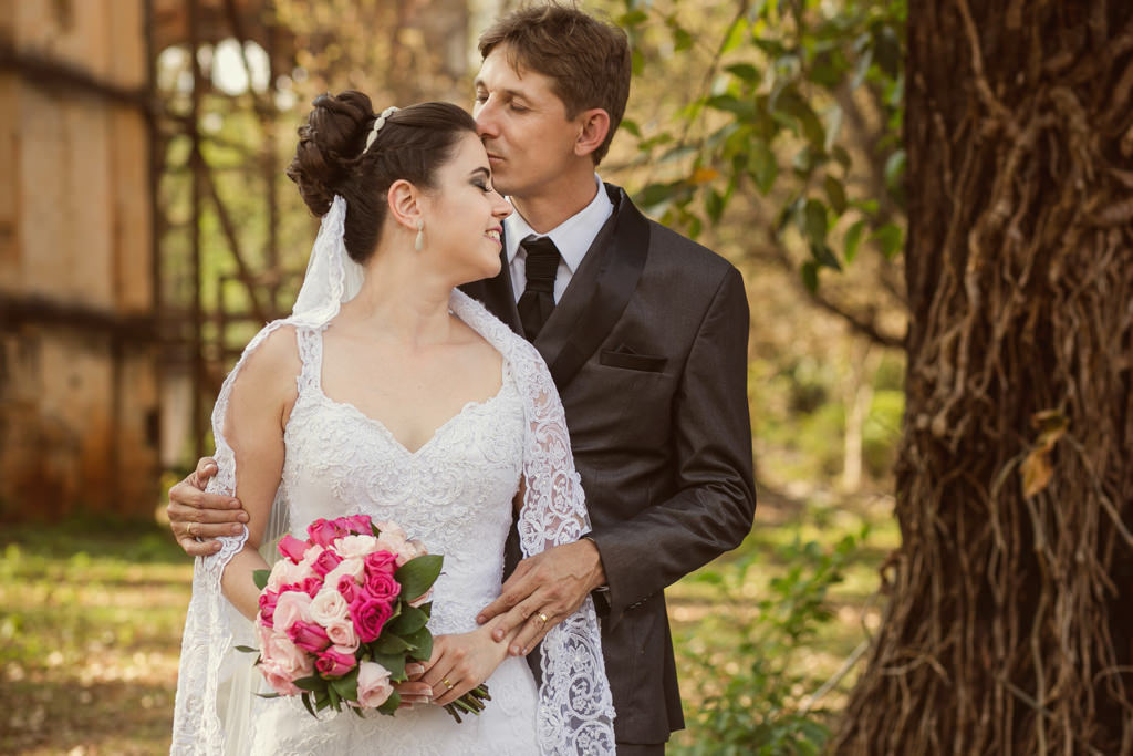 a noiva cristiane segurando o seu lindo buquê e sendo abraçada por julio